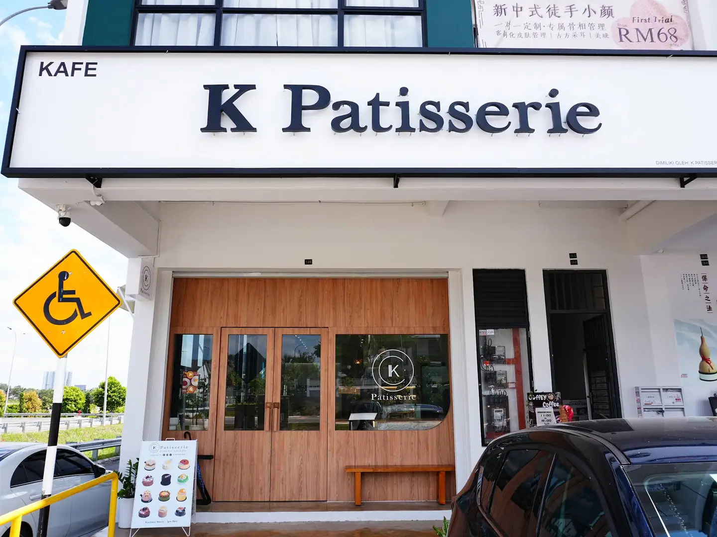 K Patisserie Johor Bahru(Austin Crest)门头:白底黑立体字招牌、橡木门与玻璃。